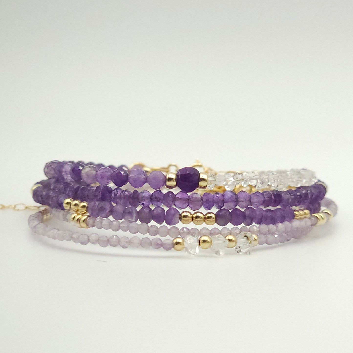 five bracelets in various amethyst beads by intentionally linked permanent jewelry. while these are not permanent jewelry, they are perfect to pair with your permanent jewelry stack.