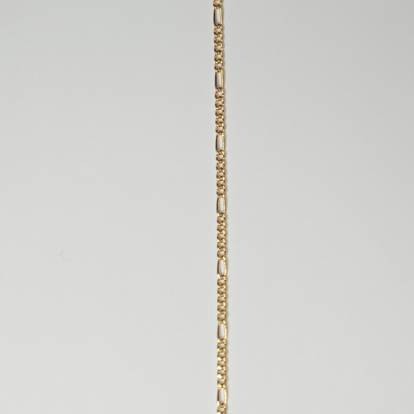 Close-up of a medium Figaro chain in 14k gold filled metal, with alternating short and elongated links—crafted for lasting wear as permanent jewelry.