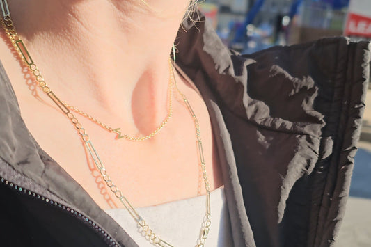 woman wearing a double rolo chain necklace that sits right below the collarbone.  
