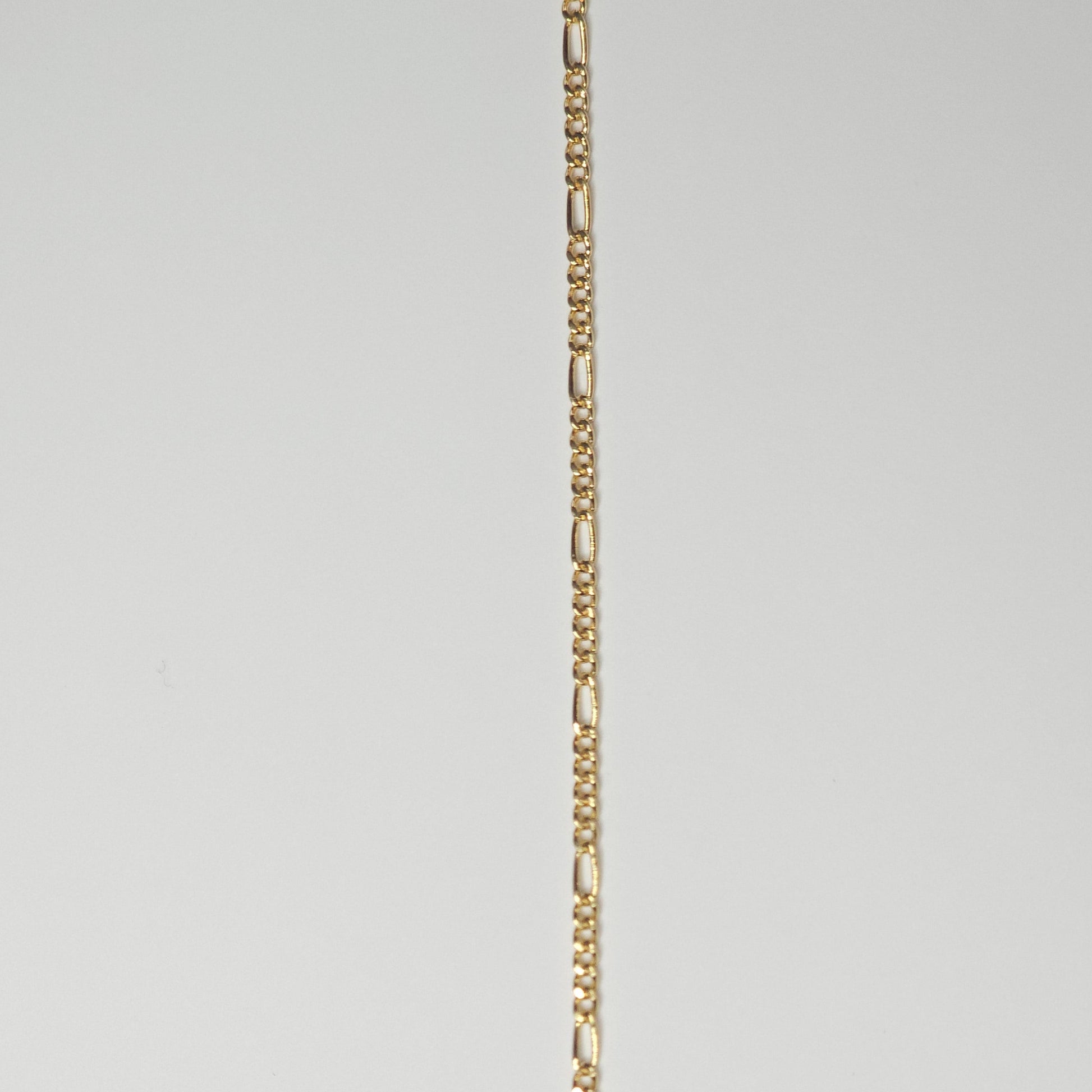 Close-up of a medium Figaro chain in 14k gold filled metal, with alternating short and elongated links—crafted for lasting wear as permanent jewelry.