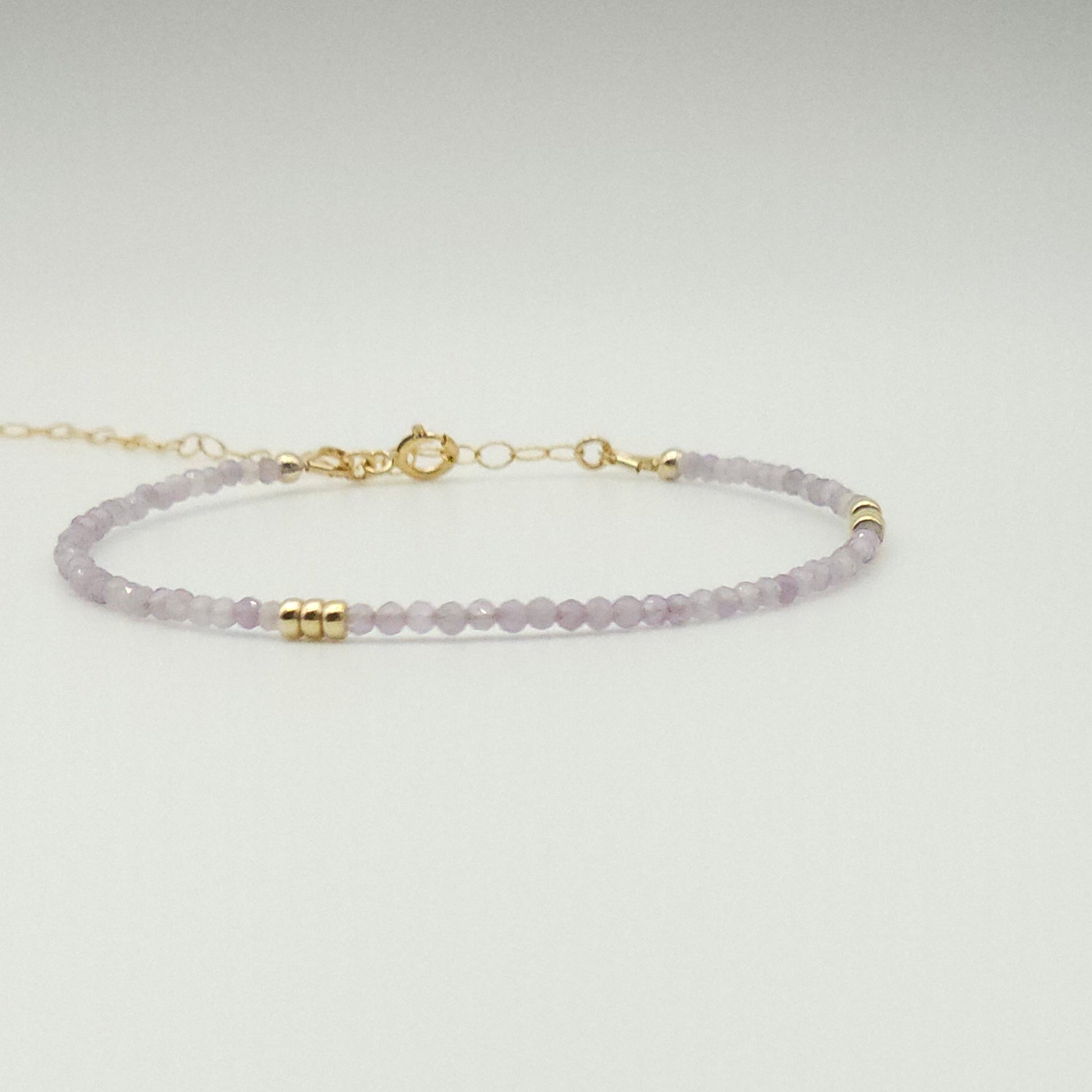 An adjustable bracelet with pink amethyst stones and gold accents, displayed against a white background.