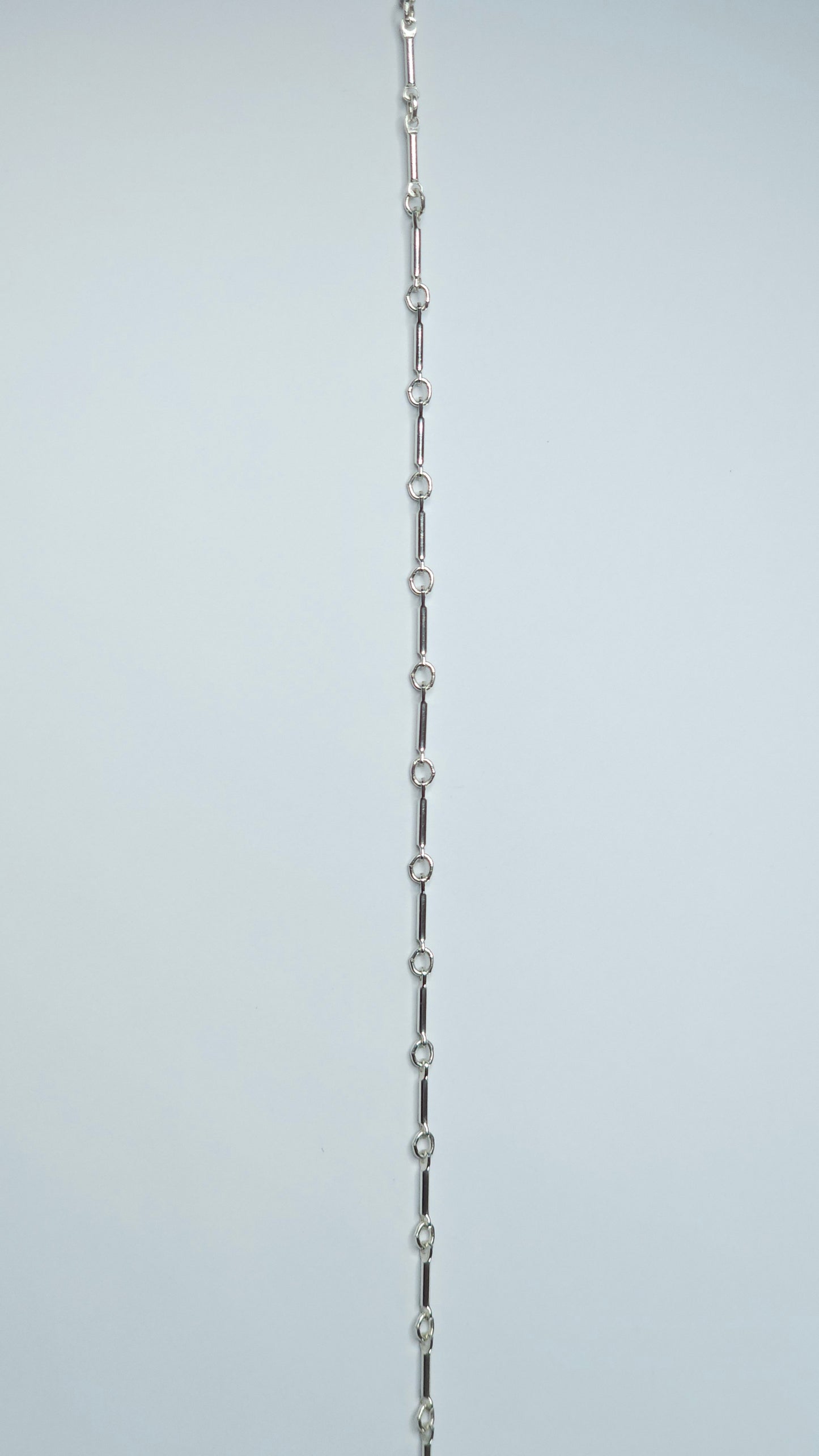 A sterling silver bar link chain, bracelet, anklet, necklace with a repeating pattern of slender bars and delicate round connectors.